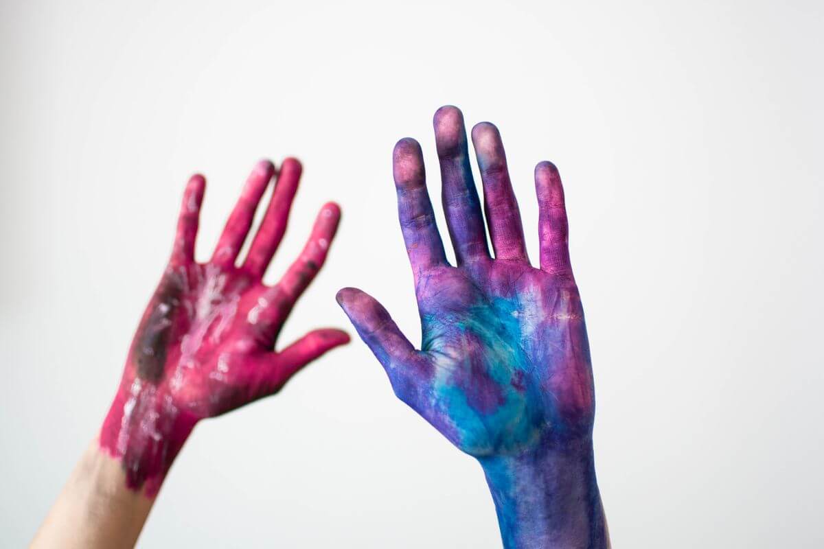Two hands covered in colorful paint — creativity and passion at work